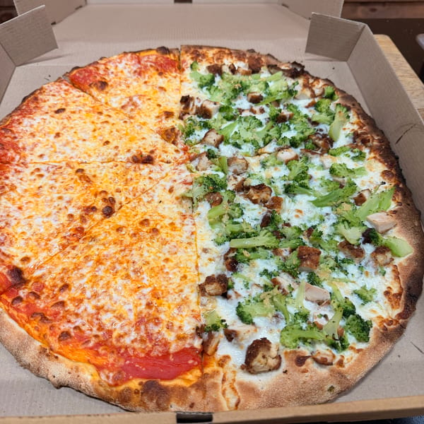 Half cheese and half chicken and broccoli pizza in a cardboard box.