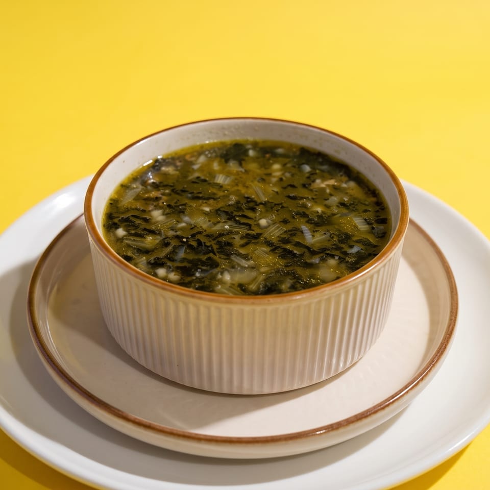 Bowl of leafy green soup with chopped vegetables on a white saucer against a bright yellow background.