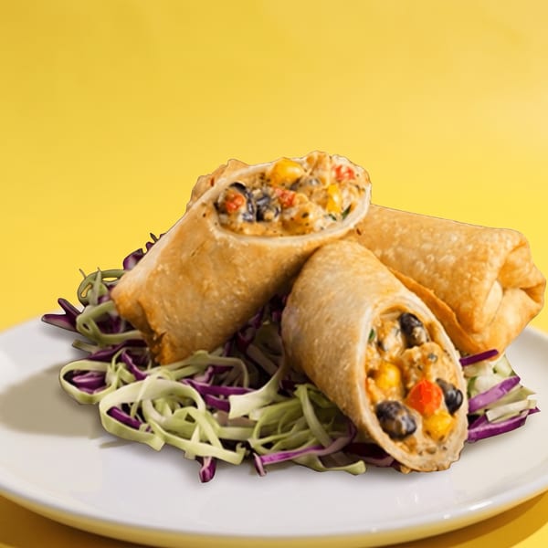 Crispy stuffed wraps filled with vegetables and black beans, served over shredded cabbage on a white plate.